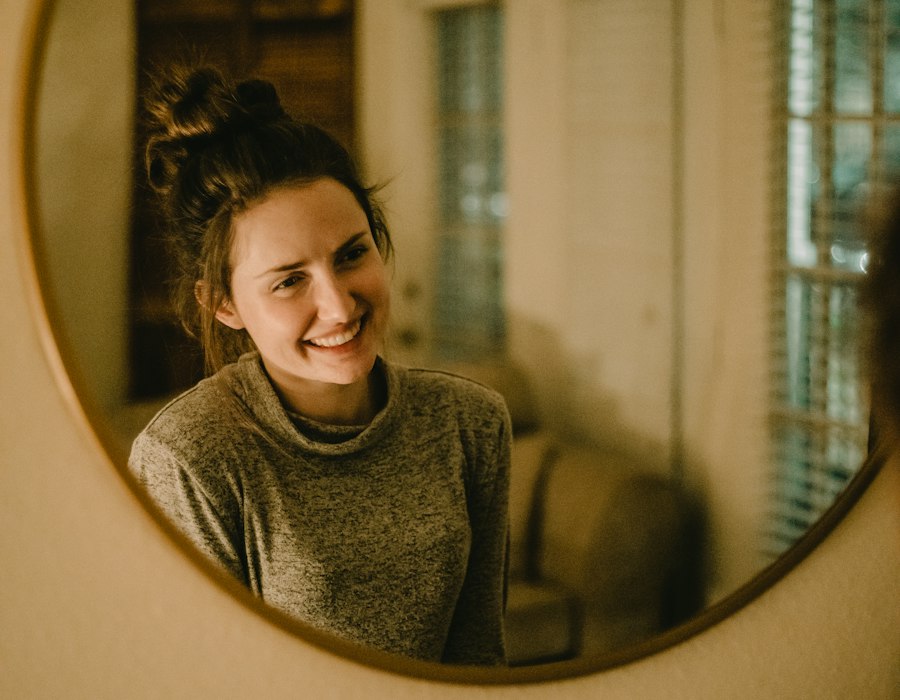 A woman smiling into a round mirror