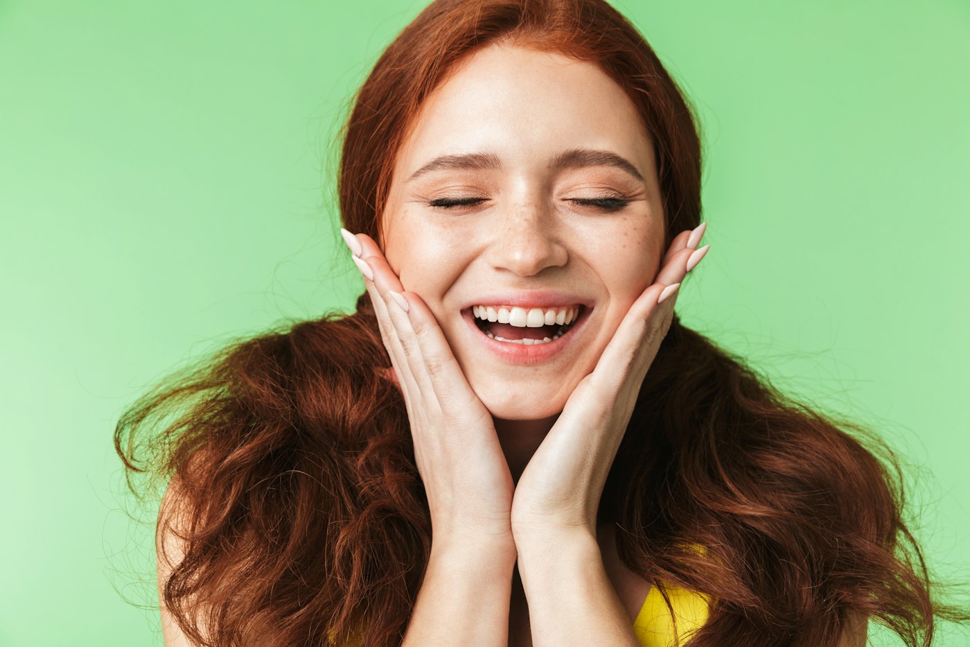A woman beaming with her hands on her cheeks